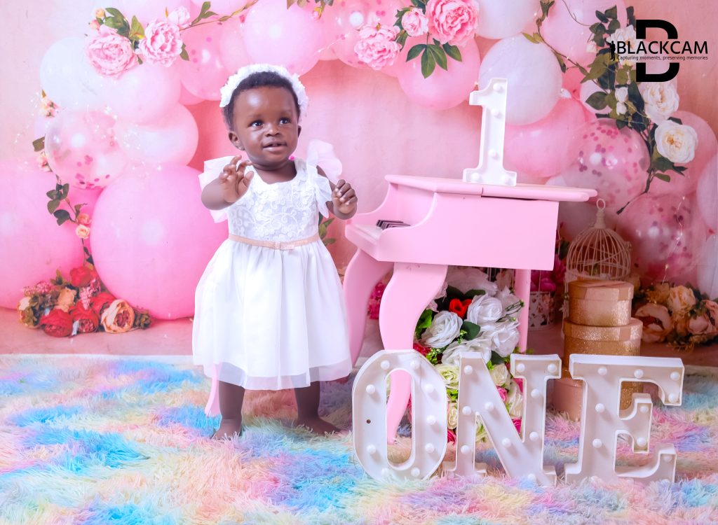 First birthday studio portrait with a white dress, pink piano and illuminated letters